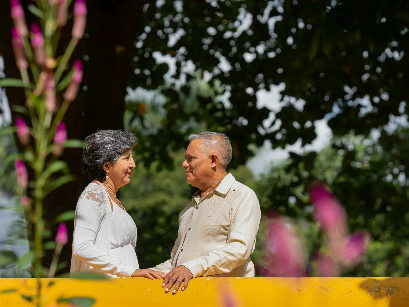 An older couple smiling at each other outdoors with both heads fully visible